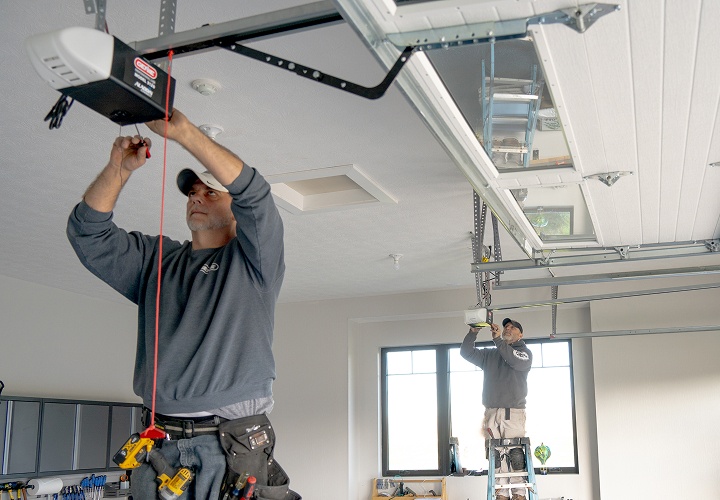 Professional technician installing a garage door opener overhead